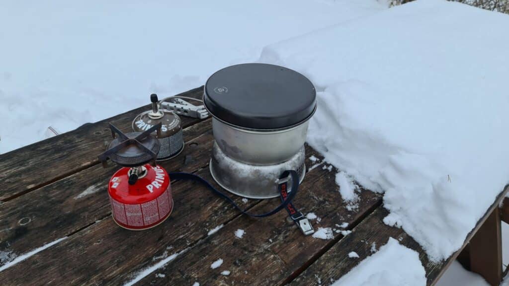 Gasolköken Primus Mimer och Trangia 25 testas på ett snötäckt bord.