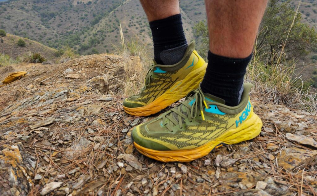 Ett par HOKA Speedgoat 5 i gult och grönt med blå detaljer