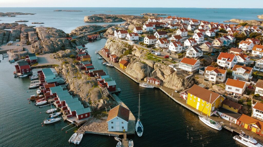 Drönarbild på Smögen - De vita husen ser ut att klättra på klipporna och de röda fiskebodarna kantar havet.