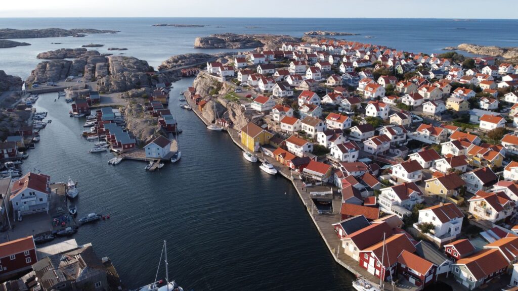 Drönarbild på Smögen - De vita husen ser ut att klättra på klipporna och de röda fiskebodarna kantar havet.