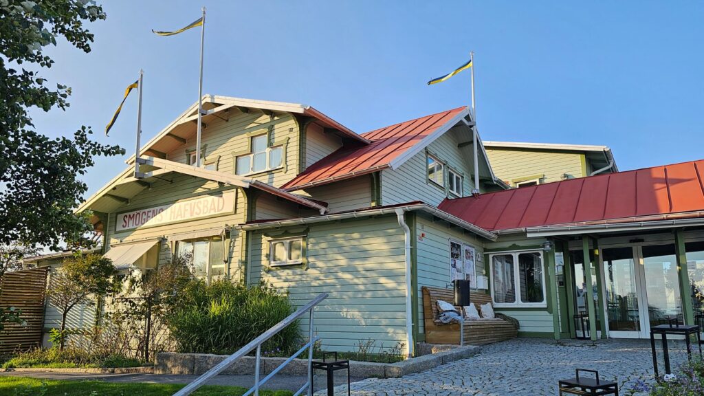 Smögens Hafvsbad, ett stort ljustgrönt trähus med tegeltak och svenska vimplar hissade.